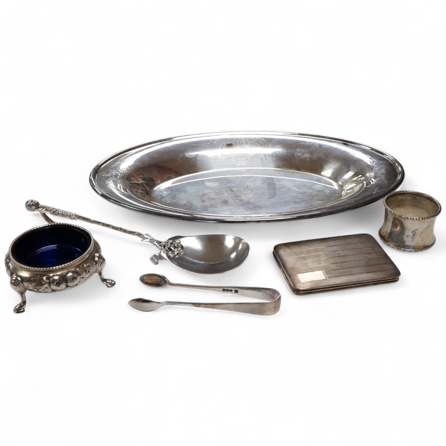 A Victorian silver bun salt, London, 1860, a later silver cigarette case, a silver napkin ring and pair of silver sugar tongs, together with a continental white metal serving spoon and a silver plated oval tray.